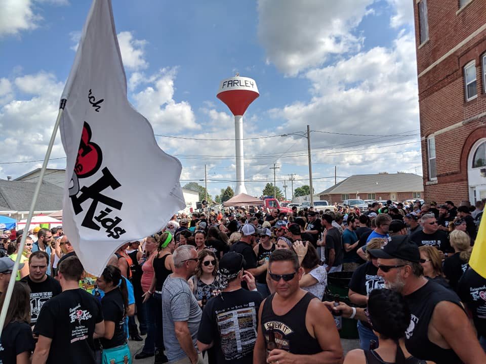 A packed crowd under the Farley water tower with a Research For The Kids flag flying