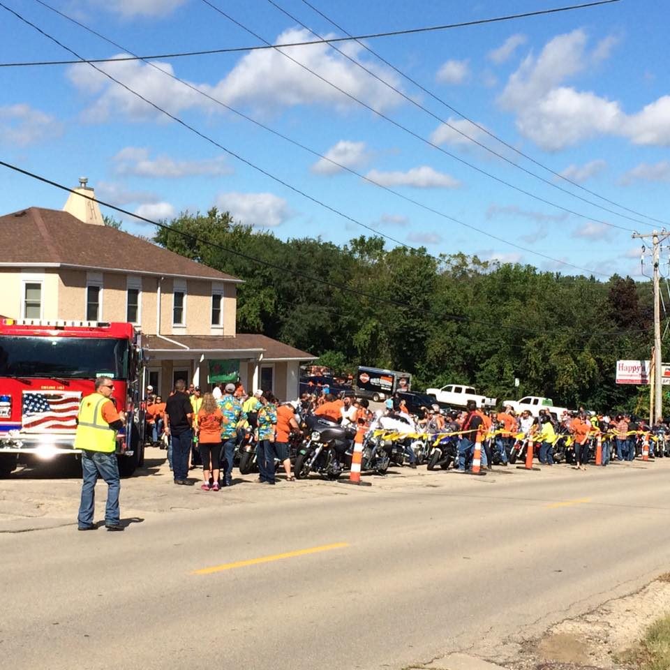 Motorcycles lined along the street outside Happy's Place with a fire truck at the front