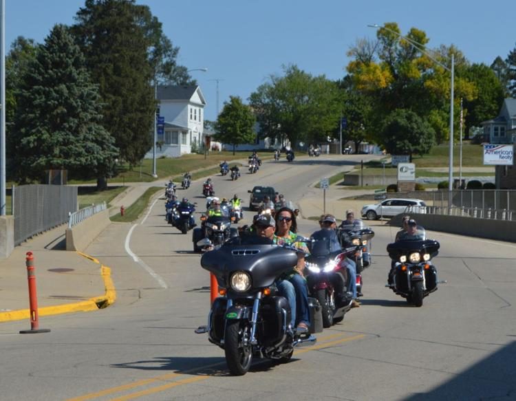 A long column of motorcycles riding through a small Iowa town on the poker run